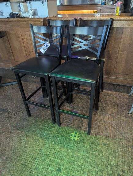 Times 4 - Black metal framed cross back bar chairs with black vinyl padded seats - showing wear on vinyl